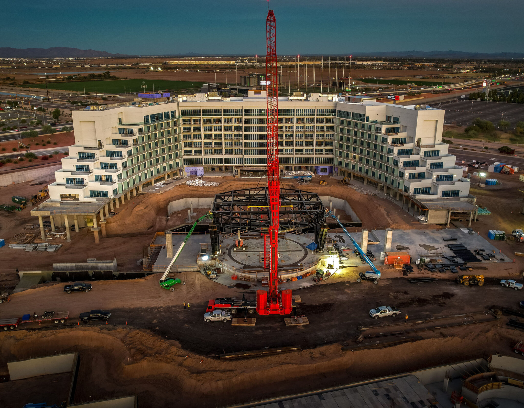Construction site with a large building and red crane in progress.