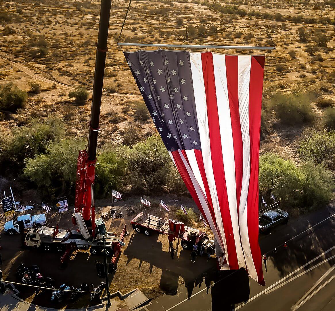 Large American flag displayed outdoors in a desert setting.
