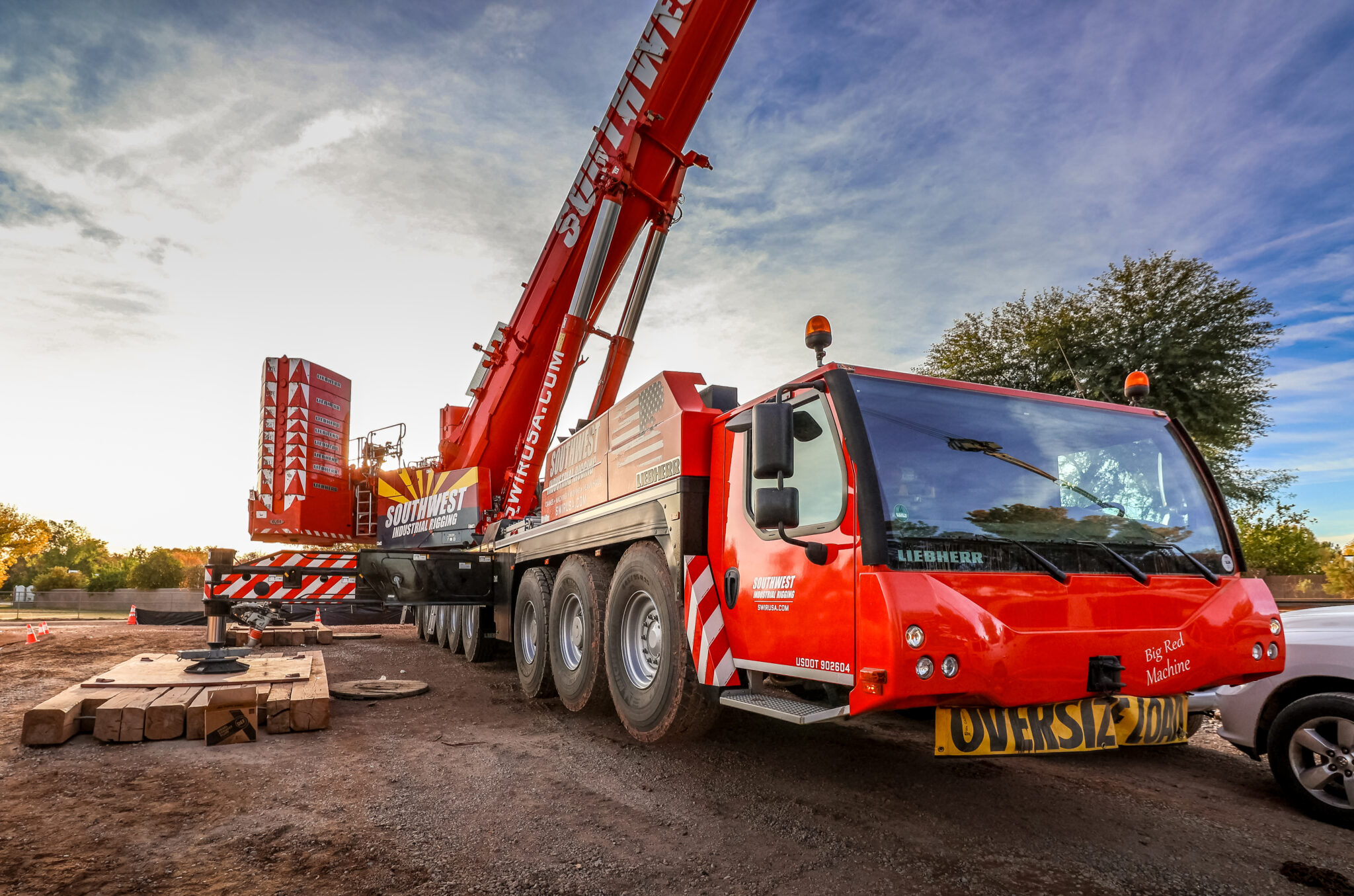 Large red crane truck at a construction site under a cloudy sky.