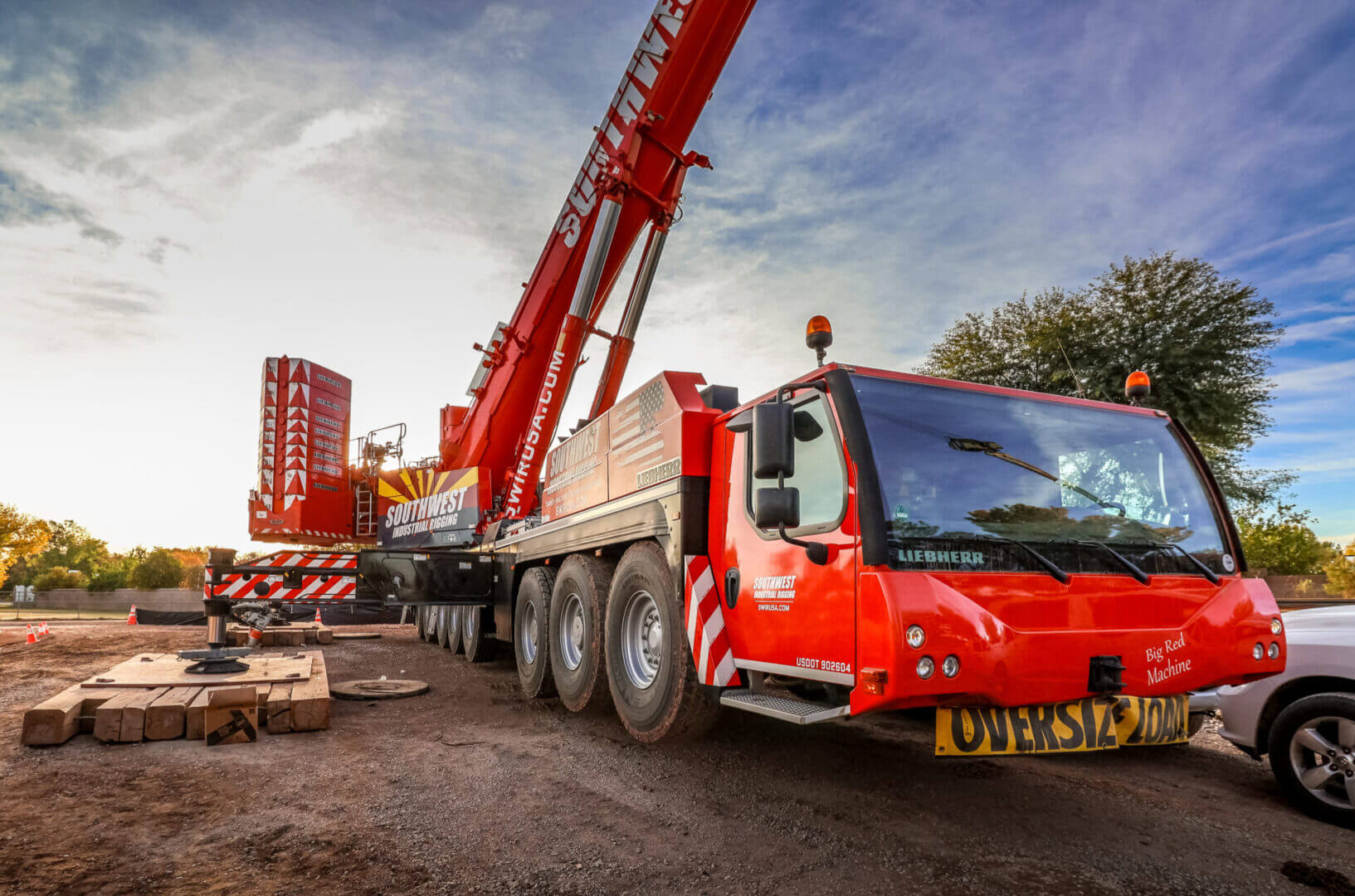 Large red crane truck at a construction site under a cloudy sky.