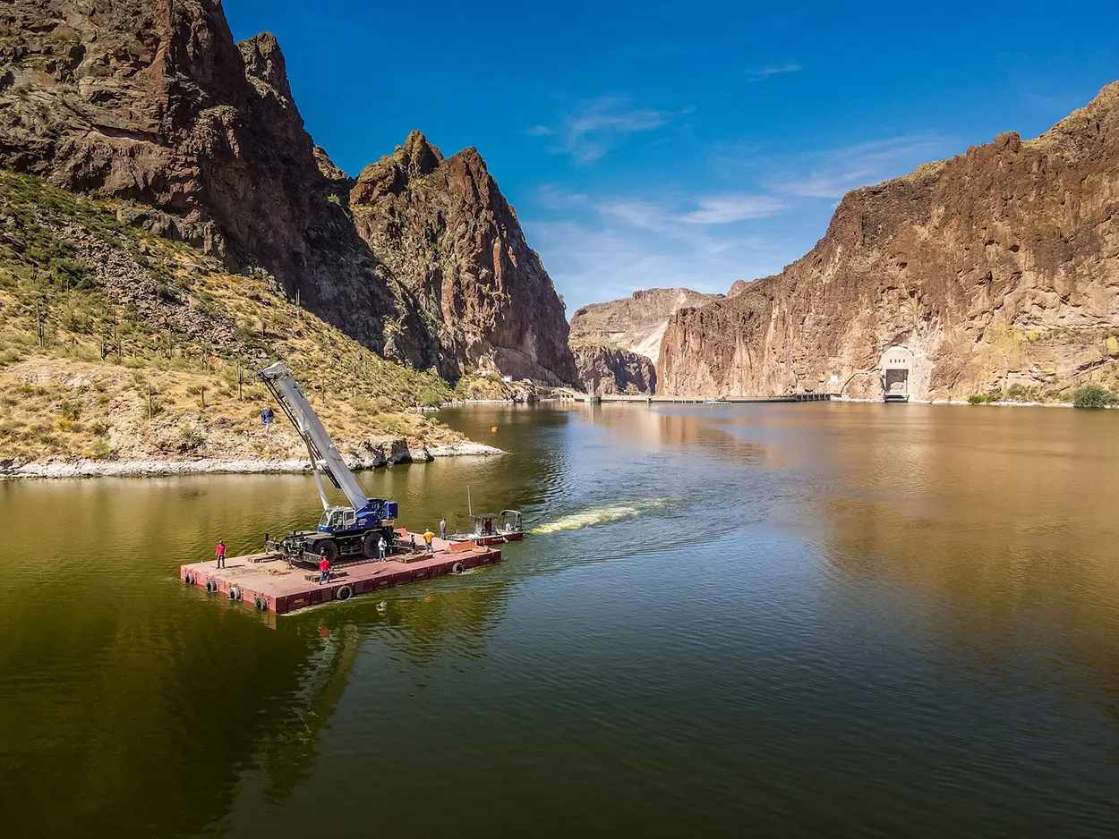 A small raft with a person floating on a calm river surrounded by rocky cliffs.