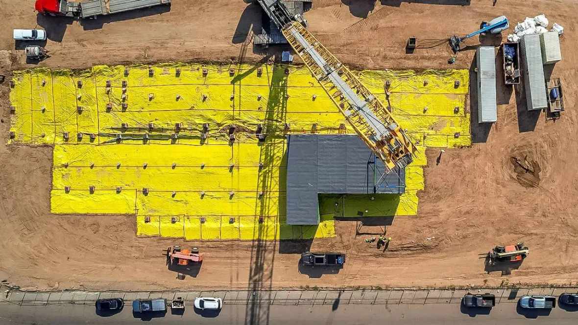 New-Projectcs2 Aerial view of construction site with yellow insulation and crane.