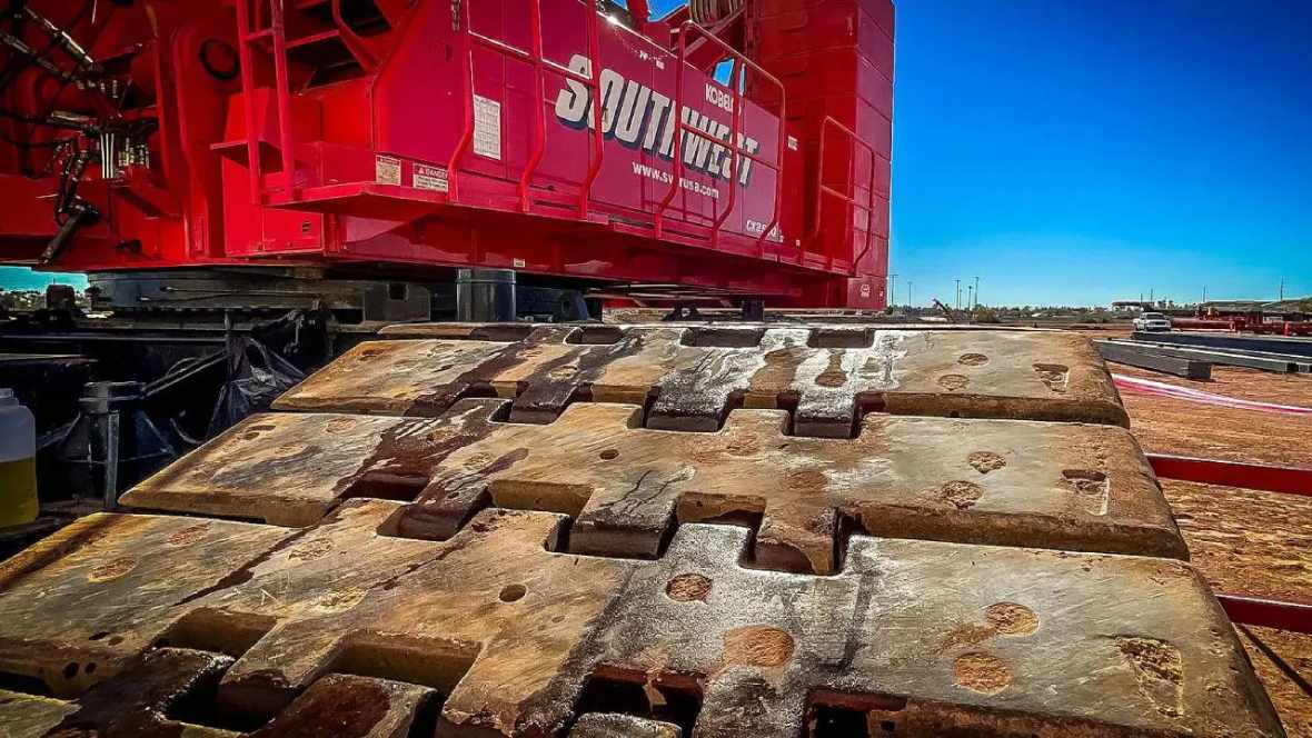 New-Projectcs5 Close-up of rusted metal tracks beneath a red industrial machine.
