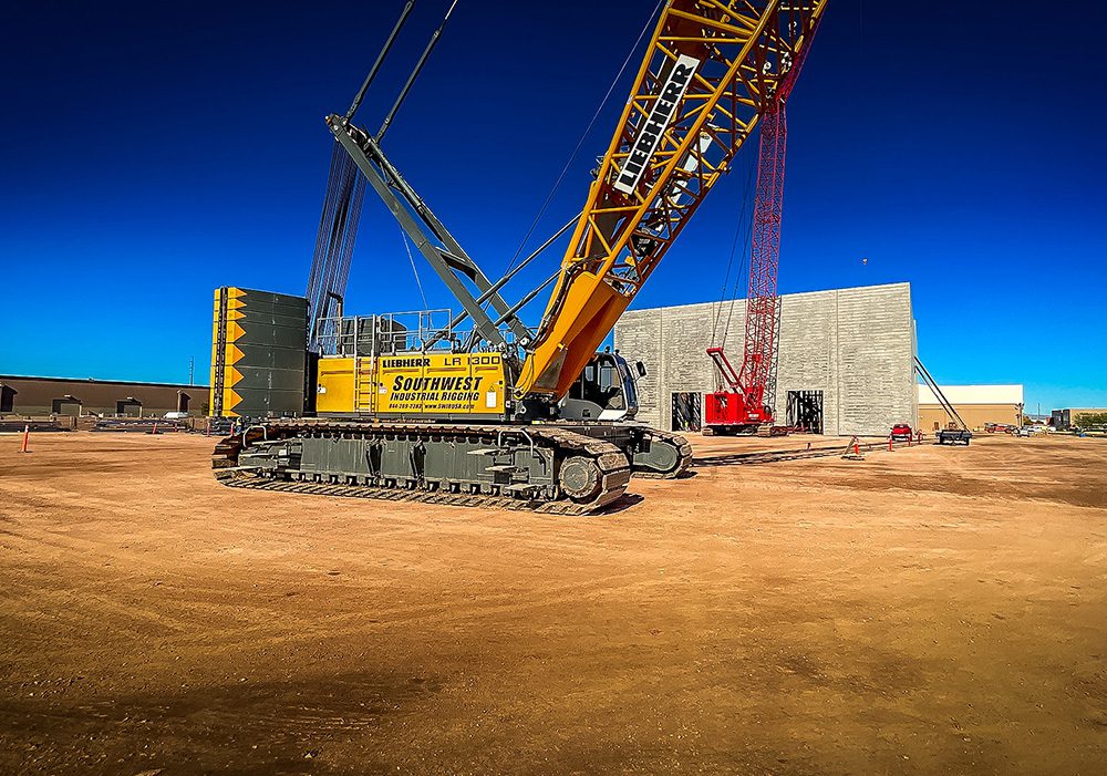 Large crawler crane at a construction site under clear blue sky.