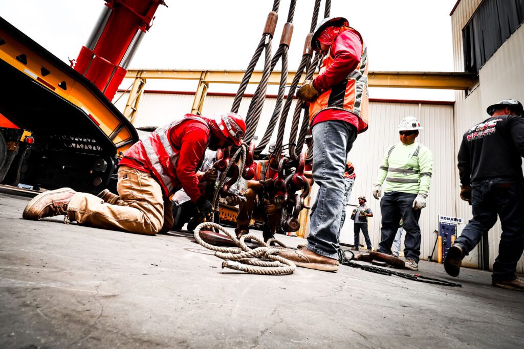 Workers in safety gear handling heavy equipment on a construction site.